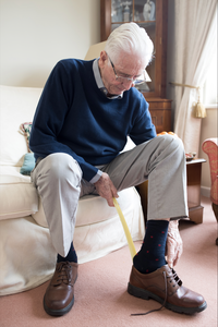 Senior Man Using Long Handled Shoe Horn To Put On Shoes