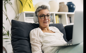 senior woman with laptop is relaxing on the sofa