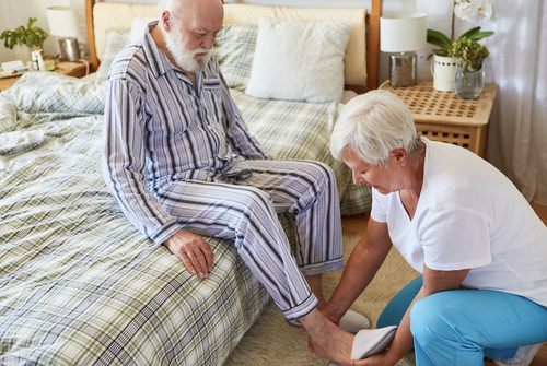 woman helping an old man to put on slippers